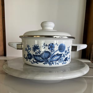 May include: White enamel saucepan with a blue and white floral design. The saucepan has a lid and two handles.