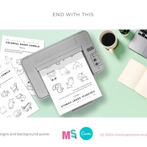 May include: A printer printing out black and white worksheets with the title "Colorful Short Vowels" and the letter "a" circled. The worksheets are on a light green surface with a laptop, a cup of coffee, and a notebook.