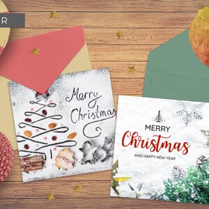 May include: Two Christmas cards on a wooden surface. One card has a hand-drawn Christmas tree made with food items on a white background. The other card has a green pine branch with snow on a white background. Both cards say "Merry Christmas".