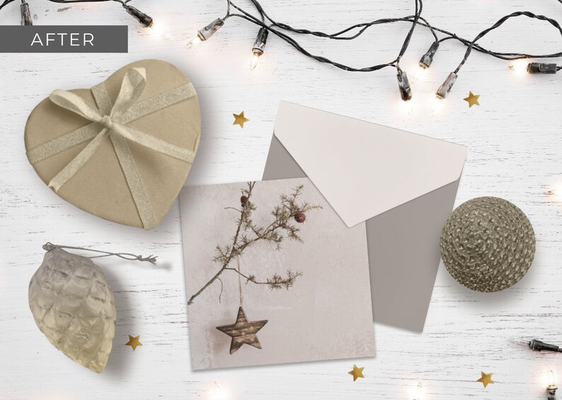 May include: A rustic Christmas card with a brown star hanging from a branch. The card is surrounded by a brown envelope, a heart-shaped box with a gold ribbon, a brown pine cone ornament, and a brown sphere ornament. The background is a white wooden surface with gold stars and a string of white lights.
