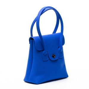 May include: A small, bright blue felt handbag with a single button closure and two top handles.