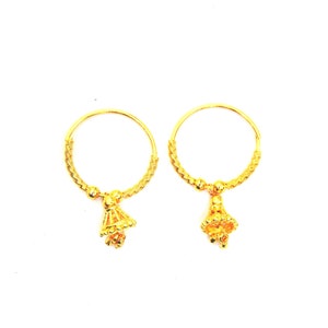 May include: A pair of gold hoop earrings with small, ornate bell-shaped charms hanging from them.