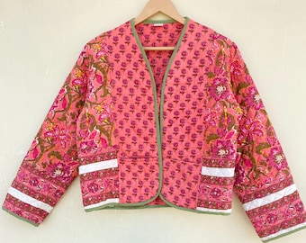 May include: A pink quilted jacket with a floral print and green trim. The jacket has a V-neck and long sleeves.