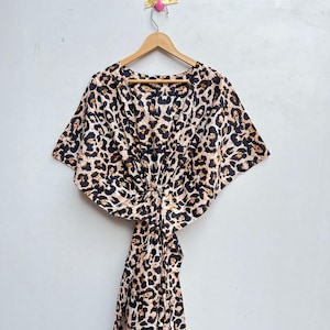 May include: A brown, black, and white leopard print maxi dress with a V-neck and short sleeves. The dress has a tie at the waist.