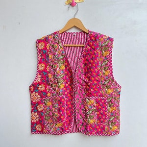 May include: A pink quilted vest with a floral print and white stripes. The vest has a V-neck and is sleeveless.