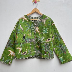 Op de afbeelding: Een groene gewatteerde jas met een jungleprint met zebra's, luipaarden, toekans en palmbomen. De jas heeft een knoopsluiting en lange mouwen.