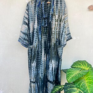 K&ouml;nnte beinhalten: Ein langer, blau-gr&uuml;ner Batik-Kimono mit einem G&uuml;rtel. Der Kimono hat eine lockere Passform und ist aus einem leichten Stoff gefertigt.