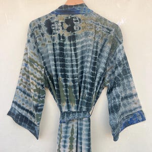 K&ouml;nnte beinhalten: Eine blaue und gr&uuml;ne Batik-Seidenrobe mit langen &Auml;rmeln und einem Bindeg&uuml;rtel.