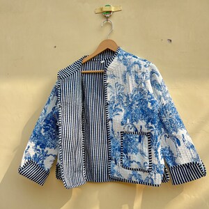 May include: A blue and white quilted jacket with a striped pattern on one side and a floral pattern on the other. The jacket has a pocket on the floral side.