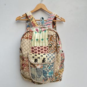 Puede incluir: Una mochila de estilo patchwork hecha de varias telas coloridas con patrones florales y geométricos. La mochila tiene un compartimento principal grande y un bolsillo frontal más pequeño.