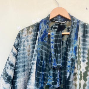 K&ouml;nnte beinhalten: Ein blaues und gr&uuml;nes Batik-Kimono mit einem passenden Bindeg&uuml;rtel. Das Kimono ist aus einem weichen, flie&szlig;enden Stoff gefertigt und hat eine lockere Passform.