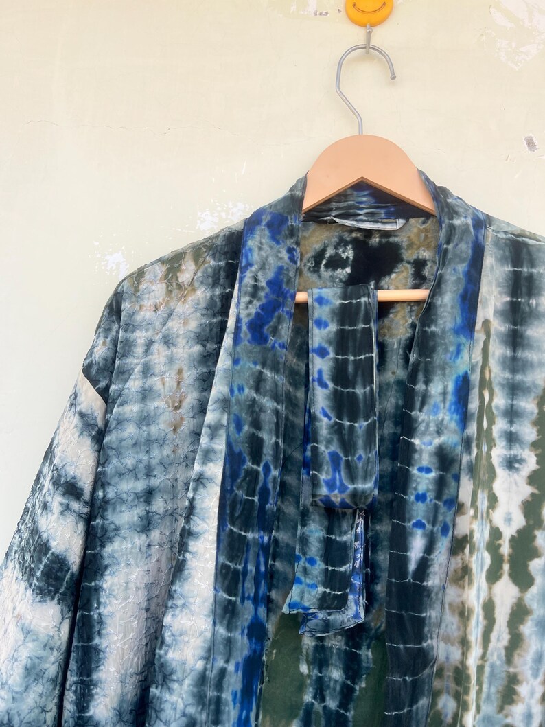 K&ouml;nnte beinhalten: Ein blaues und gr&uuml;nes Batik-Kimono mit einem passenden Bindeg&uuml;rtel. Das Kimono ist aus einem weichen, flie&szlig;enden Stoff gefertigt und hat eine lockere Passform.