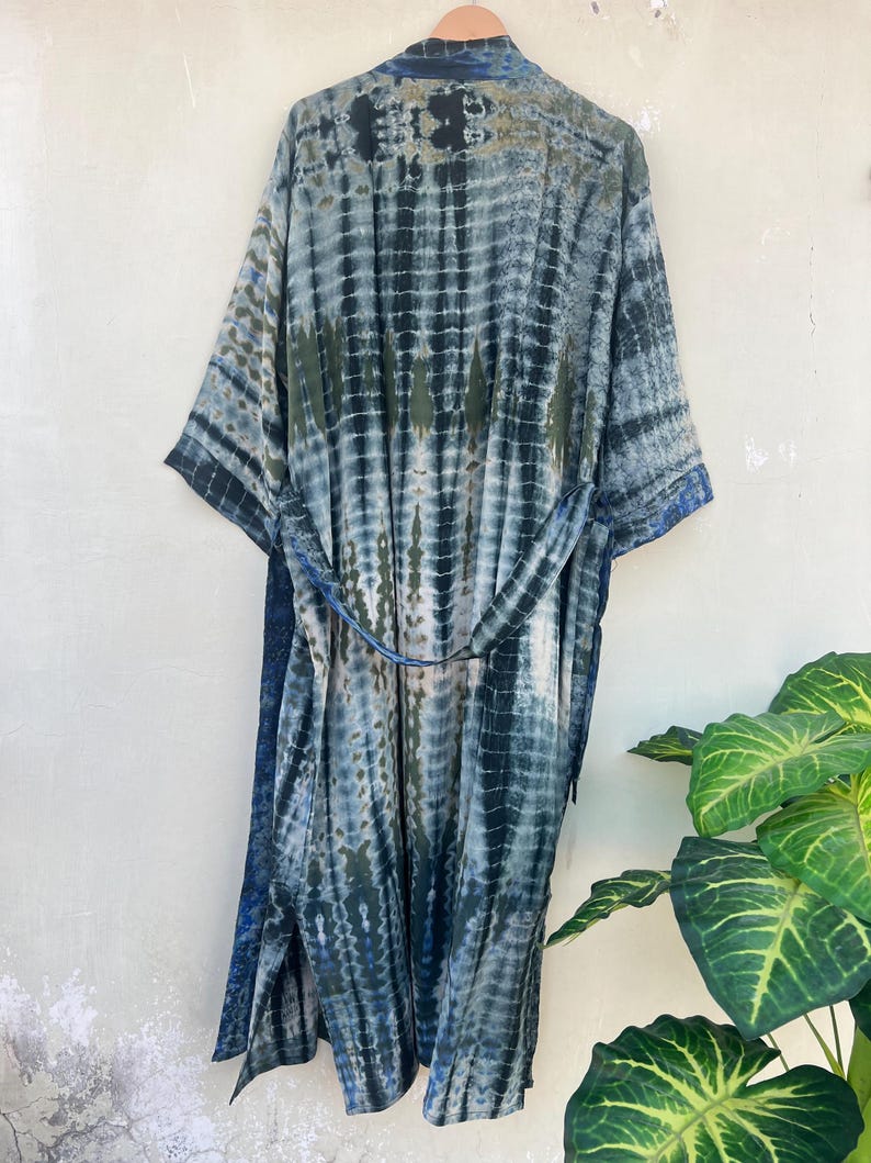 K&ouml;nnte beinhalten: Eine lange, blaue und gr&uuml;ne Batik-Robe mit einem G&uuml;rtel. Die Robe hat eine lockere Passform und ist aus einem weichen, flie&szlig;enden Stoff gefertigt.