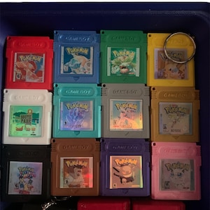 May include: A collection of 10 colorful Game Boy cartridges, each featuring a different Pokemon character. The cartridges are arranged in a grid pattern and are all in excellent condition. The cartridges are attached to a keychain, making them a fun and unique collectible.