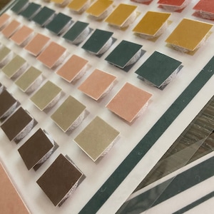 May include: A set of colourful squares with adhesive backing. The squares are arranged in rows, with each row featuring a different colour. The colours include red, orange, yellow, green, blue, and brown. The squares are perfect for crafting and decorating.
