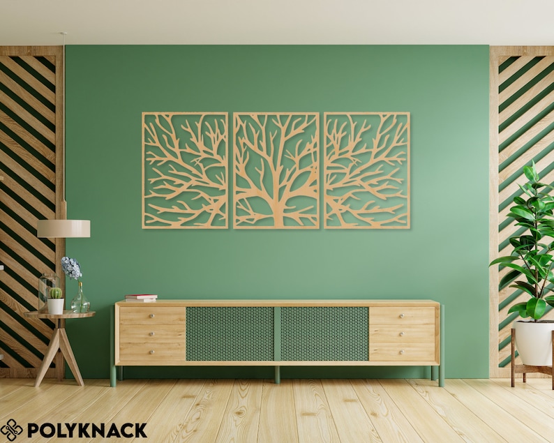 May include: Three-panel wooden wall art featuring a tree branch design. The artwork is made of light-colored wood and is mounted on a green wall. The room also includes a wooden cabinet, a side table, and a potted plant.