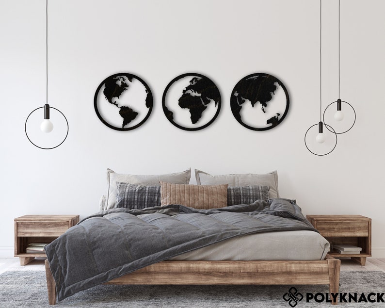 May include: Three black metal wall decor pieces shaped like globes, each depicting a different continent. The globes are hanging on a white wall above a wooden bed frame with a gray duvet and pillows.