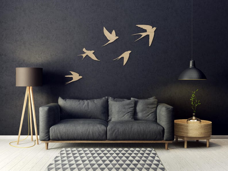 May include: A modern living room with a dark gray sofa, wooden side table, and a patterned rug. Five wooden swallows are mounted on the dark wall. A floor lamp and pendant light complete the decor.