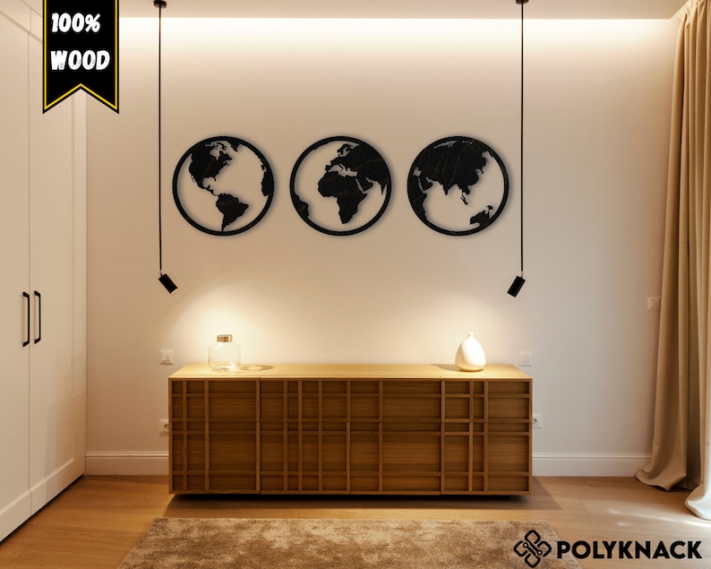 May include: Three black wooden wall decorations shaped like the Earth, hanging on a white wall with a wooden dresser underneath. The text "100% WOOD" is in the top left corner of the image.