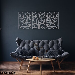 May include: Three-piece metal wall art featuring a tree branch design. The artwork is silver and mounted on a dark blue wall above a gray sofa. The room is decorated with a wooden coffee table and a vase with pink flowers.