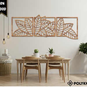Op de afbeelding: Drie houten wanddecoratiepanelen met een bladontwerp. De panelen zijn lichtbruin en hebben een natuurlijke houtlook. De panelen zijn in een rij gerangschikt en zijn gemonteerd op een witte muur.