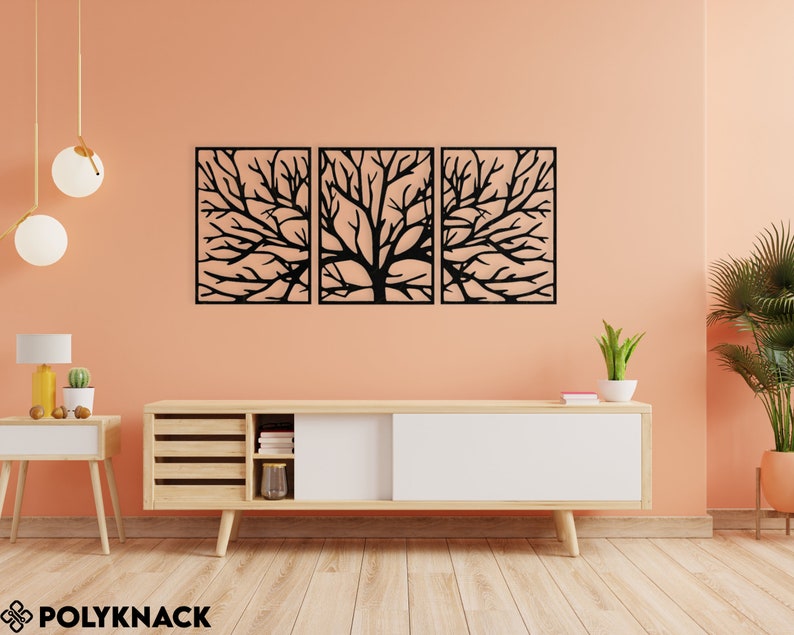 May include: A triptych of black metal tree branch wall art. Each panel is rectangular with a detailed cutout design of a tree's branches. The artwork is mounted on a peach-colored wall above a wooden cabinet.