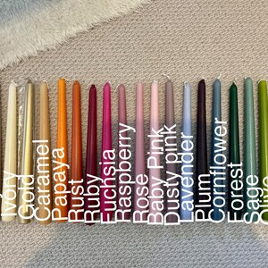 K&ouml;nnte beinhalten: Eine Sammlung von achtzehn Stabkerzen in einem Farbspektrum, darunter Oyster, Ivory, Gold, Caramel, Papaya, Rust, Ruby, Fuchsia, Raspberry, Rose, Baby Pink, Dusty Pink, Lavender, Plum, Cornflower, Forest, Sage, Olive und Jade.