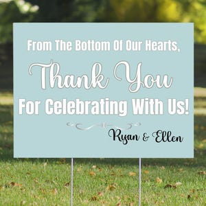 May include: A light blue thank you sign with white text that reads "From The Bottom Of Our Hearts, Thank You For Celebrating With Us!" and "Ryan & Ellen".
