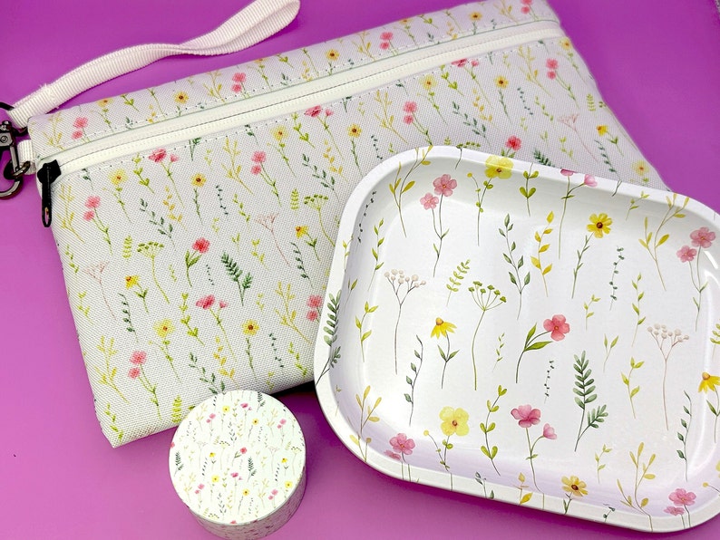 Peut inclure: Une pochette zipp&eacute;e en toile blanche avec un motif floral, un plateau en c&eacute;ramique blanche avec un motif floral et un petit r&eacute;cipient rond blanc avec un motif floral.