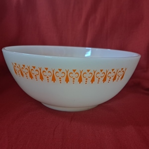 May include: A white mixing bowl with an orange geometric pattern around the rim.