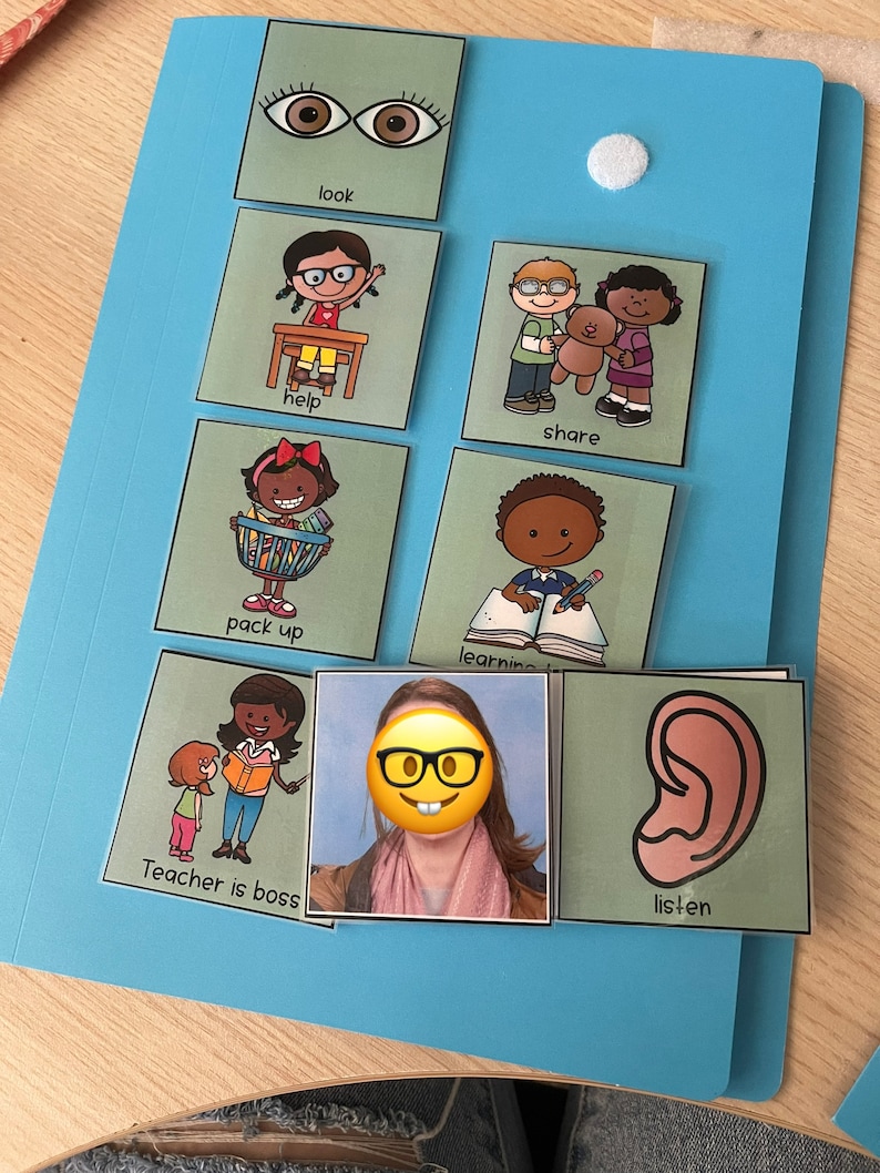Op de afbeelding: Een lichtblauwe map met een witte klittenbandstip, met verschillende groene kaarten. De kaarten bevatten illustraties en tekst zoals "look", "help", "share", "pack up", "learning", "Teacher is boss" en "listen".