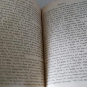 Pode incluir: Um livro aberto com p&aacute;ginas amareladas e envelhecidas. O texto &eacute; pequeno e denso, sugerindo uma obra cl&aacute;ssica ou vintage. A encaderna&ccedil;&atilde;o &eacute; vis&iacute;vel e o livro parece bem usado. As p&aacute;ginas est&atilde;o ligeiramente curvadas, indicando idade e uso.