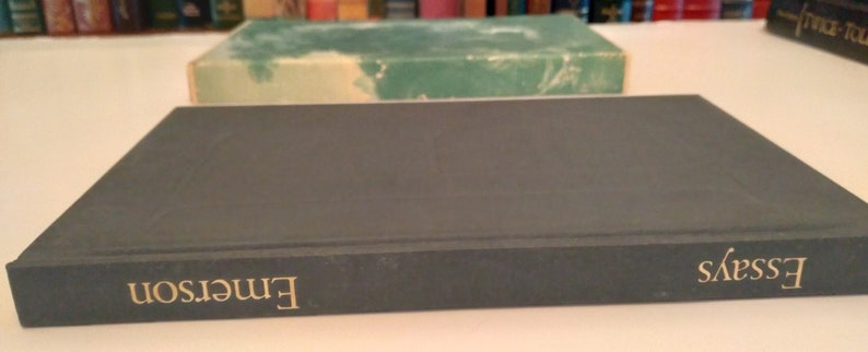 May include: A dark blue hardcover book with the title "Essays" in gold lettering on the spine. The author's name, "Emerson", is printed in gold lettering on the front cover.