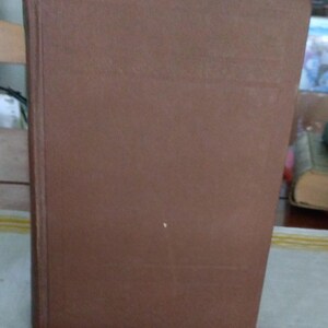 Pode incluir: Um livro de capa dura castanho com uma apar&ecirc;ncia desgastada. A capa do livro &eacute; de uma cor castanha lisa e suave, e a lombada &eacute; vis&iacute;vel no lado esquerdo. As bordas do livro mostram sinais de desgaste, sugerindo que &eacute; bem usado.