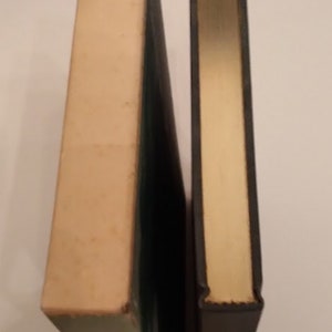 May include: Two hardcover books standing side by side. The book on the left has a white cover with a green spine. The book on the right has a black cover with a gold spine.