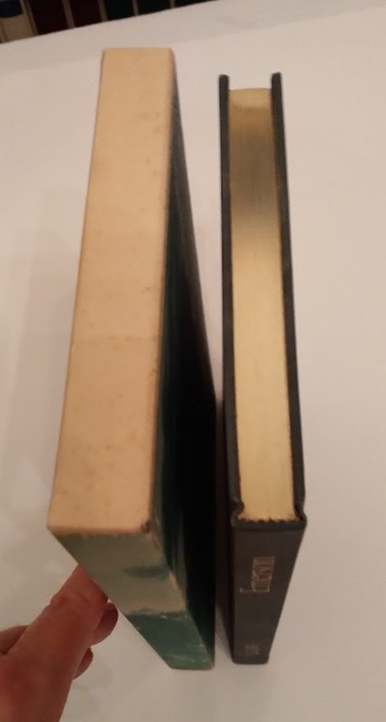 May include: Two hardcover books standing side by side. The book on the left has a white cover with a green spine. The book on the right has a black cover with a gold spine.
