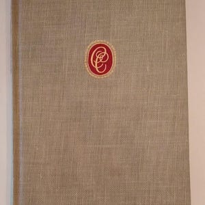 May include: A beige linen-textured book with a red and gold emblem on the cover. The book has a simple, classic design, with a slightly rounded spine. The cover is a solid, neutral color.
