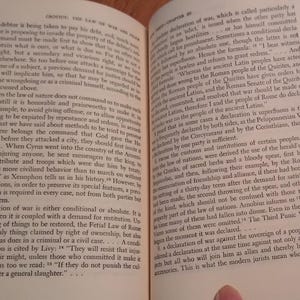 May include: Open book with text on aged paper. The pages display columns of printed text, likely from a historical or academic work. The text is in English, with the title "CRITICS: THE LAW OF WAR AND PEACE".