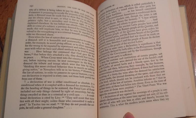 May include: Open book with text on aged paper. The pages display columns of printed text, likely from a historical or academic work. The text is in English, with the title "CRITICS: THE LAW OF WAR AND PEACE".
