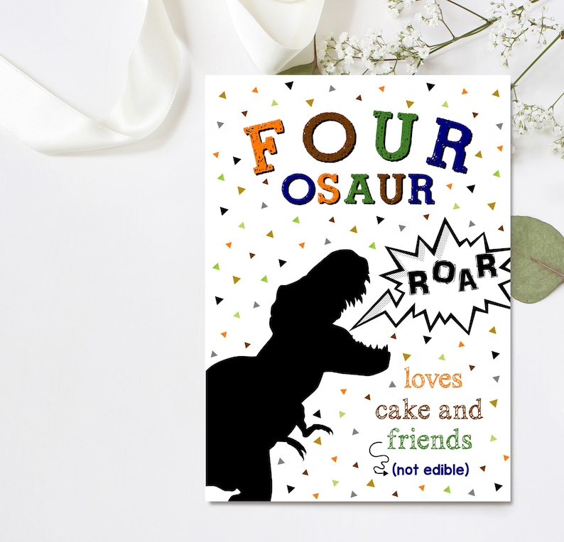 May include: A white card with a black dinosaur silhouette, a speech bubble with the word "ROAR" and the text "FOUR OSAUR loves cake and friends (not edible)". The background is white with colorful confetti.
