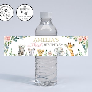 May include: Water bottle label with a floral design and a pink heart. The label says "Amelia's third birthday" and features a giraffe, zebra, elephant, and lion.