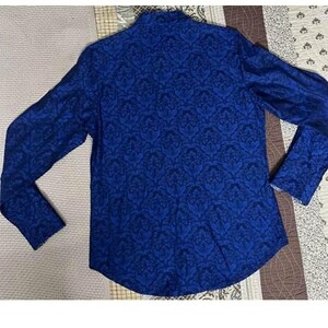May include: A long-sleeved blue shirt with a dark blue floral pattern. The shirt is made of a soft material and has a classic design. The shirt is laid flat on a patterned surface.