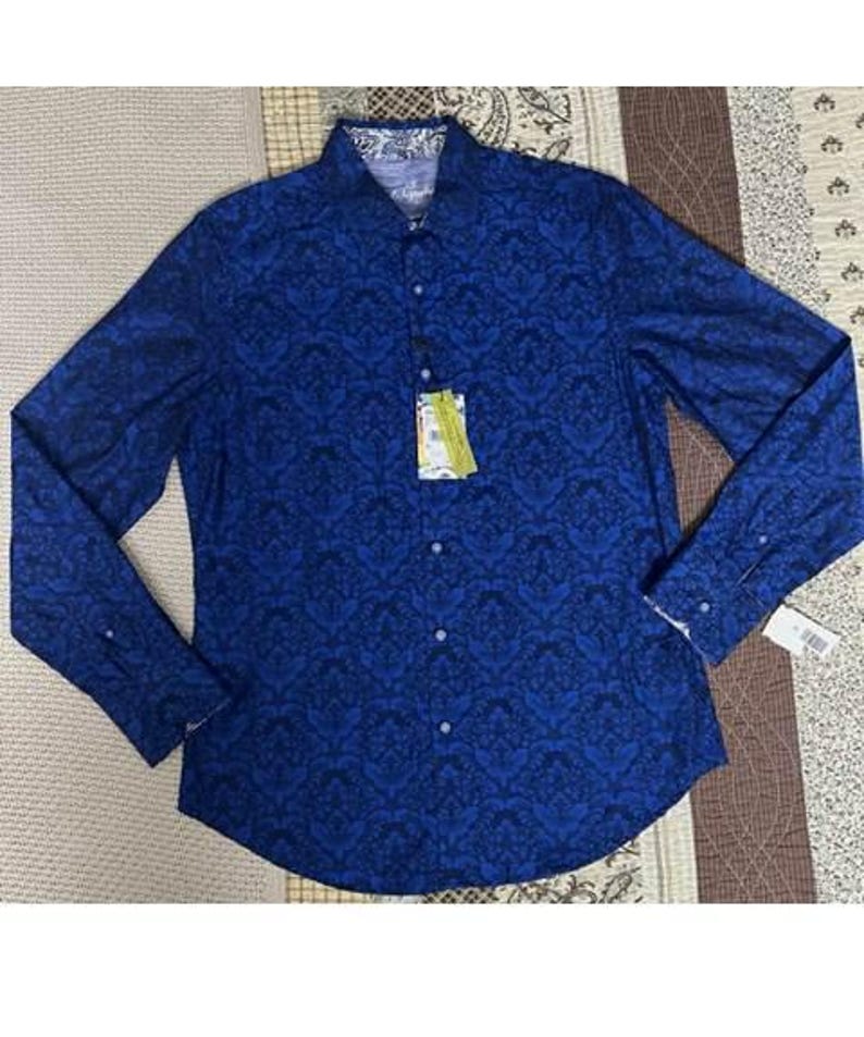 May include: A long-sleeved button-down shirt in a deep blue hue, adorned with a dark blue floral pattern. The shirt features a classic collar and cuffs with a contrasting design. A tag is attached, indicating the garment's brand and size.