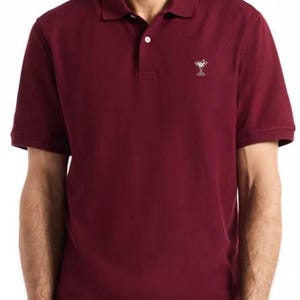 May include: A white ceramic mug with a black handle and the text "But First, Coffee" in a black, bold font. The mug is on a white surface.