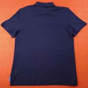 Puede incluir: Polo azul marino con mangas cortas y cuello. La camisa tiene un dise&ntilde;o cl&aacute;sico y est&aacute; hecha de una tela suave. Una peque&ntilde;a etiqueta azul es visible en la parte inferior izquierda del dobladillo.