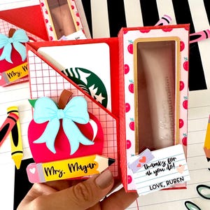 Puede incluir: Una taza de cerámica blanca con un asa negra y el texto "But First, Coffee" en negro, con una fuente de estilo manuscrito. La taza está sobre una superficie blanca.