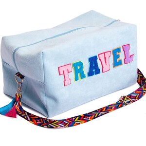 Puede incluir: Una bolsa de viaje azul claro con una aplicaci&oacute;n de la palabra "TRAVEL" de colores y una correa multicolor con un borla.