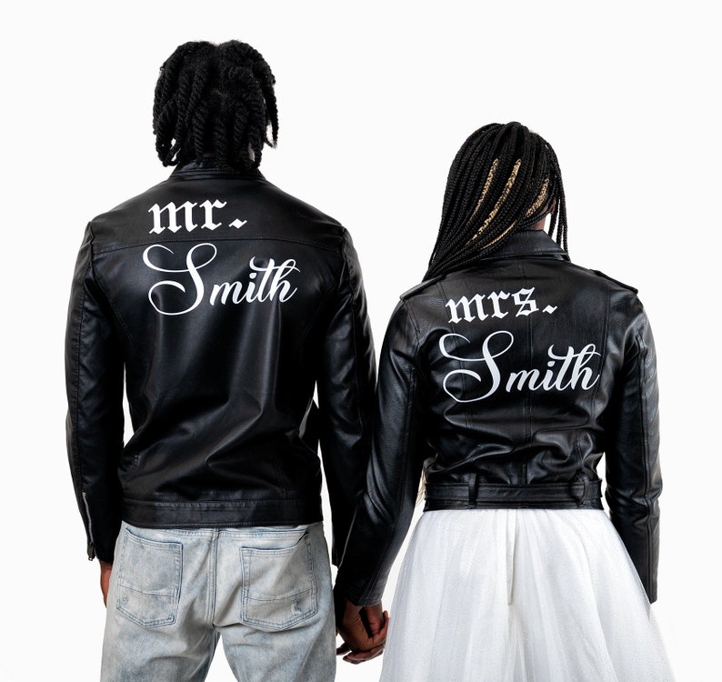 K&ouml;nnte beinhalten: Ein Paar tr&auml;gt schwarze Lederjacken mit wei&szlig;em Text auf dem R&uuml;cken. Die Jacke des Mannes sagt "mr. Smith" und die Jacke der Frau sagt "mrs. Smith".