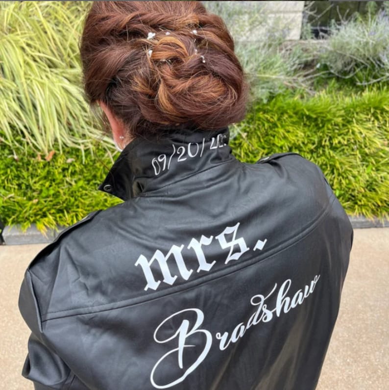 K&ouml;nnte beinhalten: Schwarze Lederjacke mit dem Text "mrs. Bradshaw" und dem Datum "09/20/2023" auf der R&uuml;ckseite gestickt.