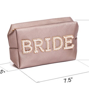May include: A light pink satin cosmetic bag with the word "BRIDE" spelled out in gold letters with pearl accents. The bag measures 7.5 inches wide, 5.5 inches tall, and 2.5 inches deep.